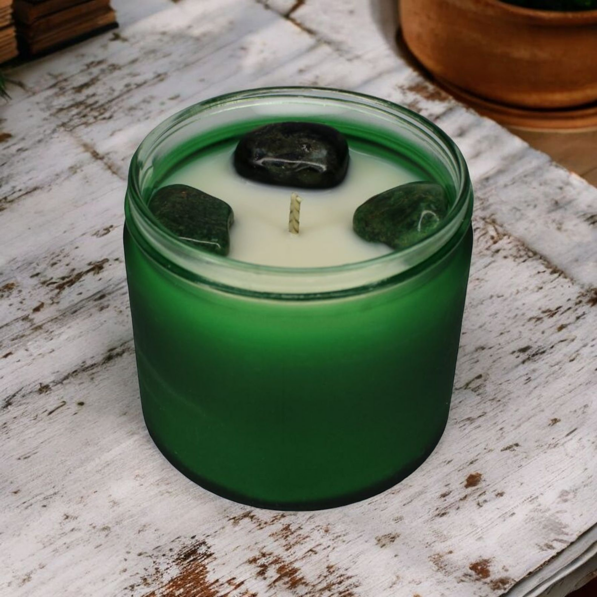 Kindness Candle infused with green quartz and kambala jasper crystals, floral almond scent, handmade in a glass container.